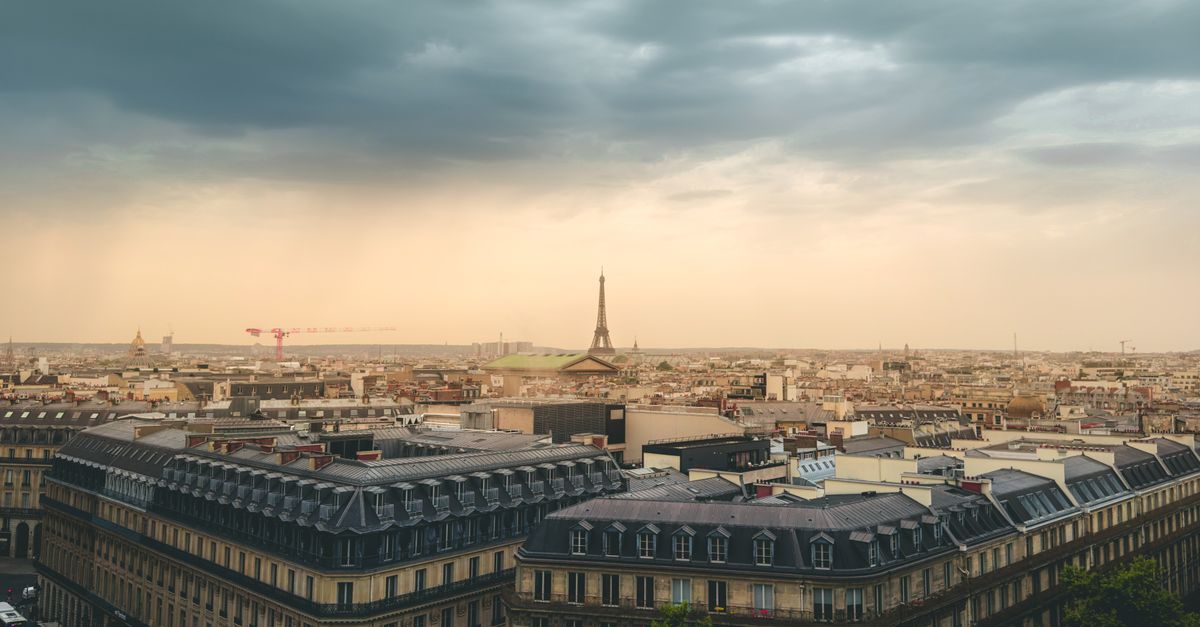 Beautiful view of Paris skyline featuring the Eiffel Tower under dramatic clouds.